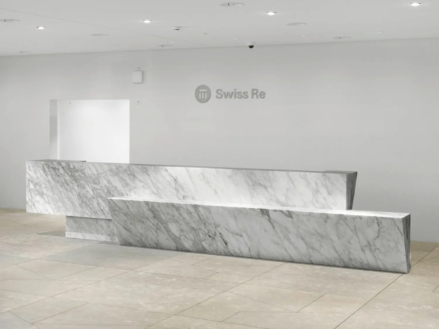 The reception desk is made out of a single piece of pale marble.