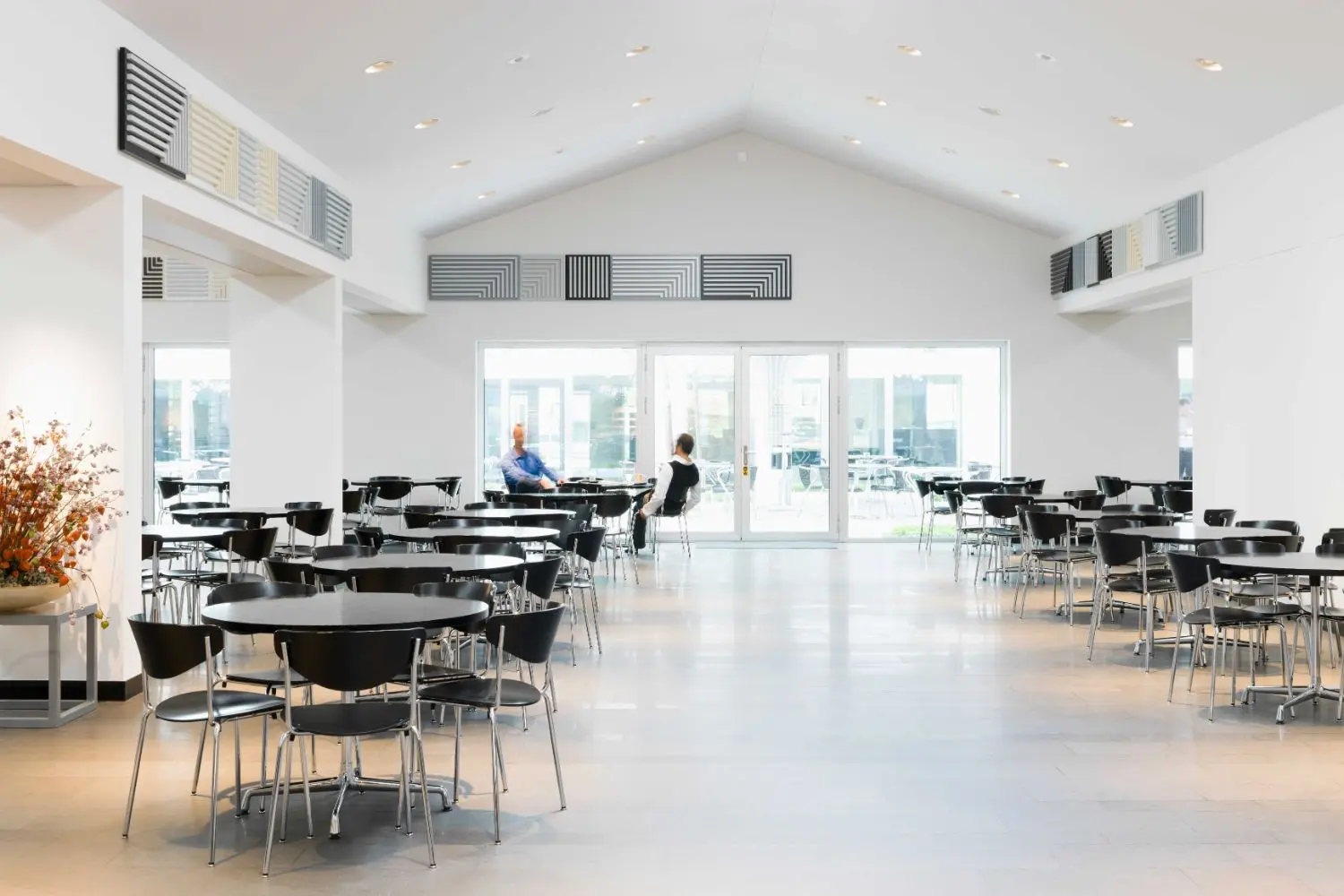 Above eye level hang 100 MDF panels of different square sizes, ranging from black to white, showing abstract patterns.