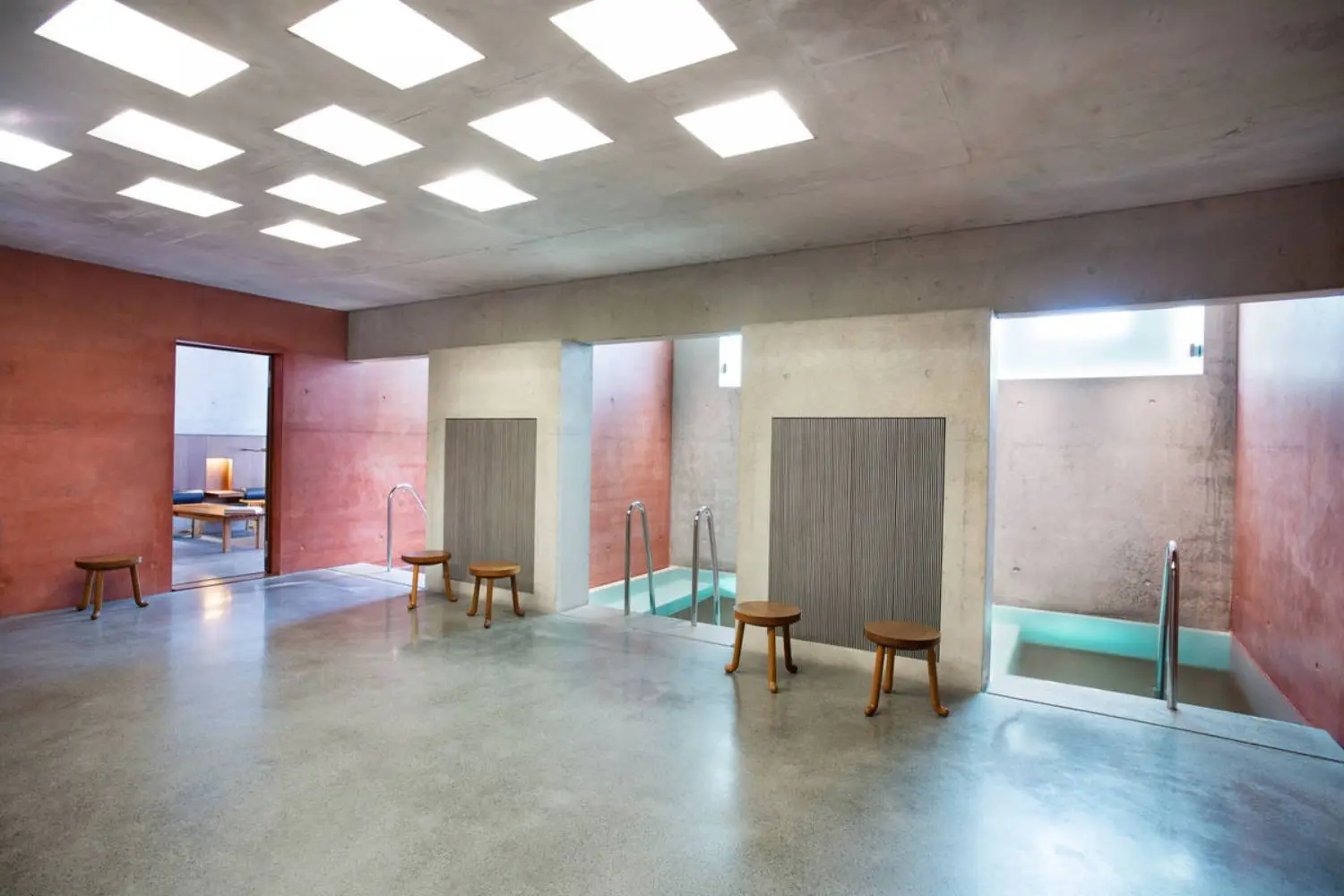 A concrete room with two spa pools and chairs.