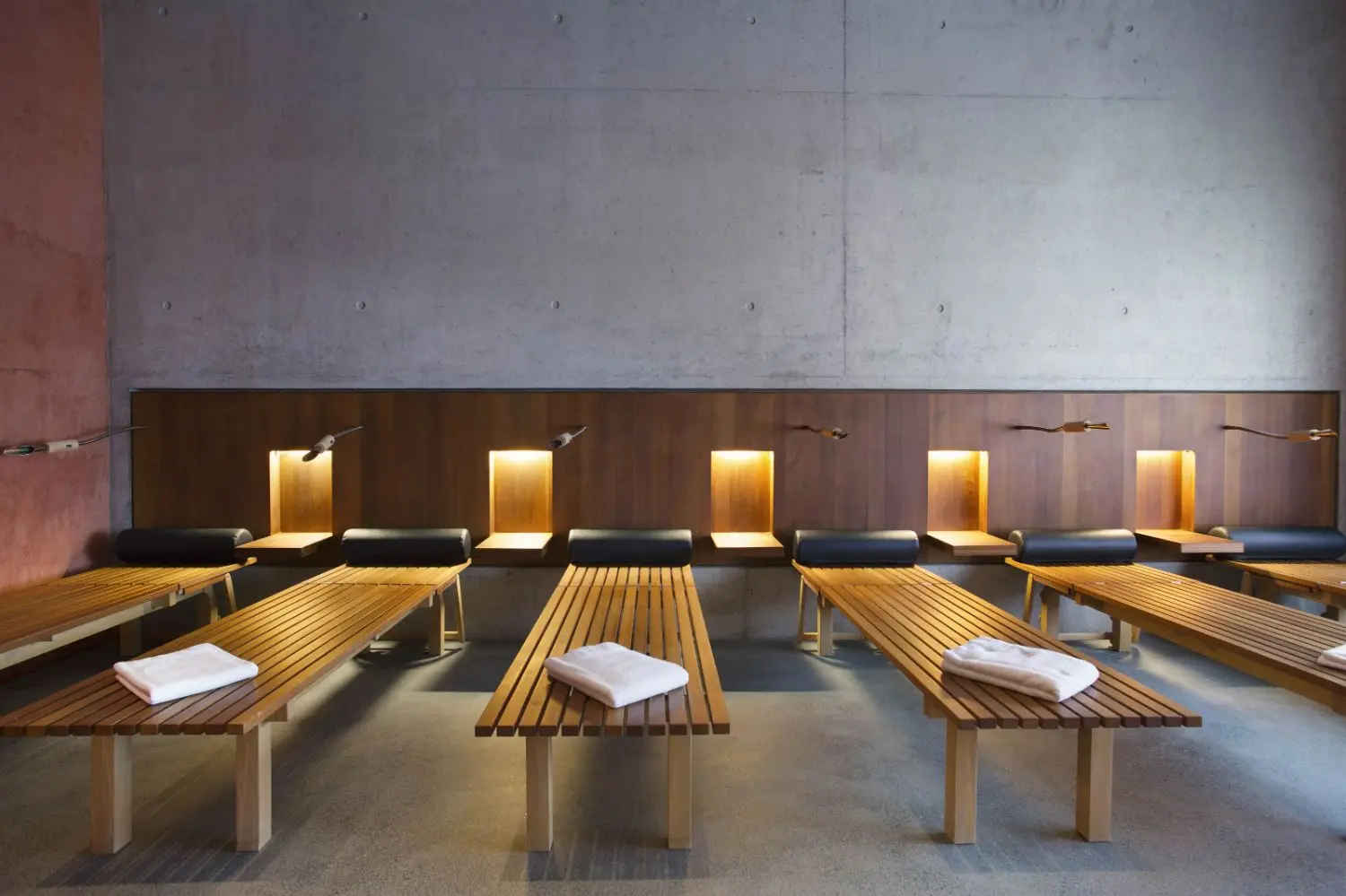 Rows of wooden spa beds with white towels on top and mood lights in the back.
