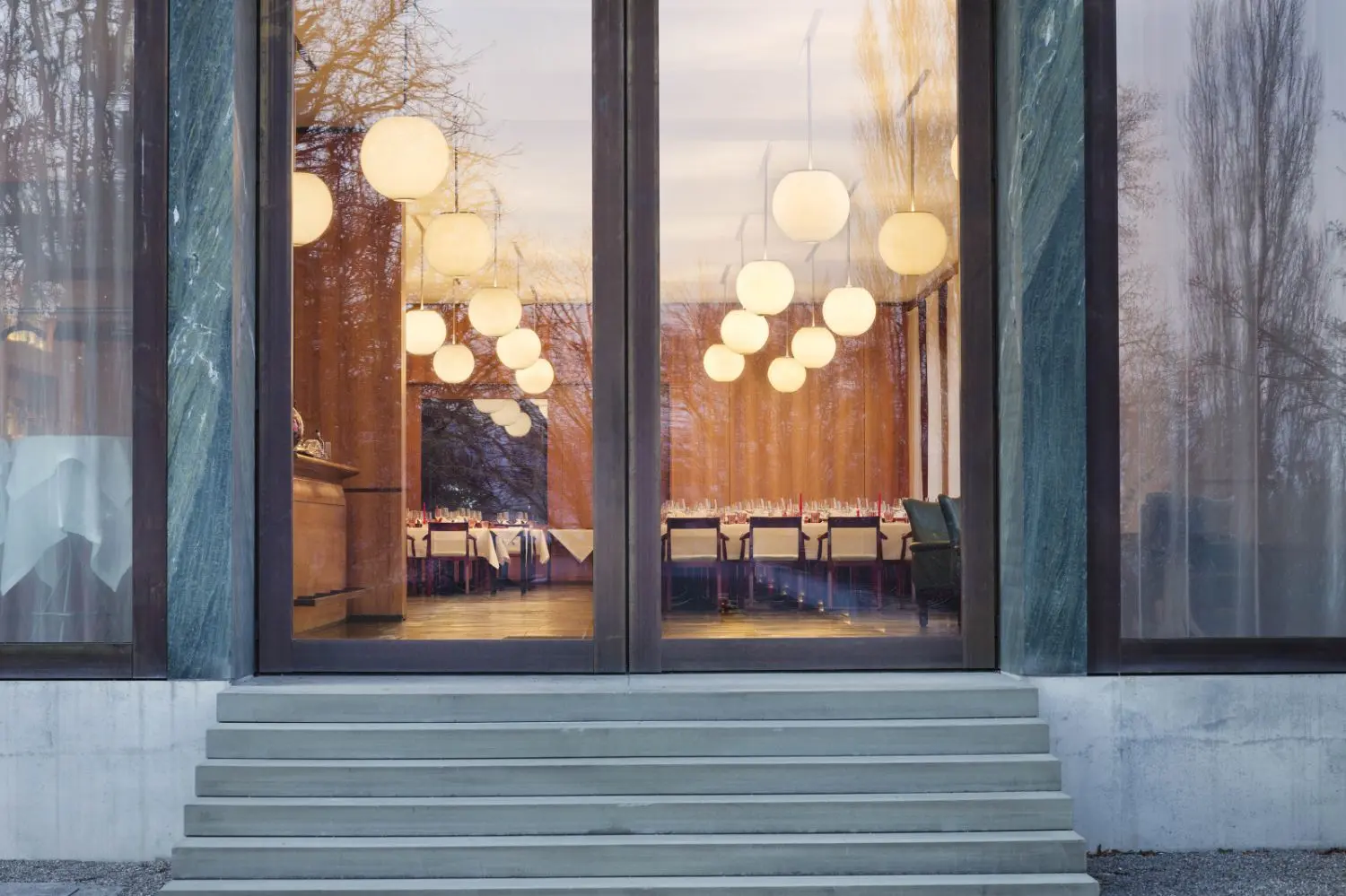 Bright lights shine through a glass double door entrance with stairs.